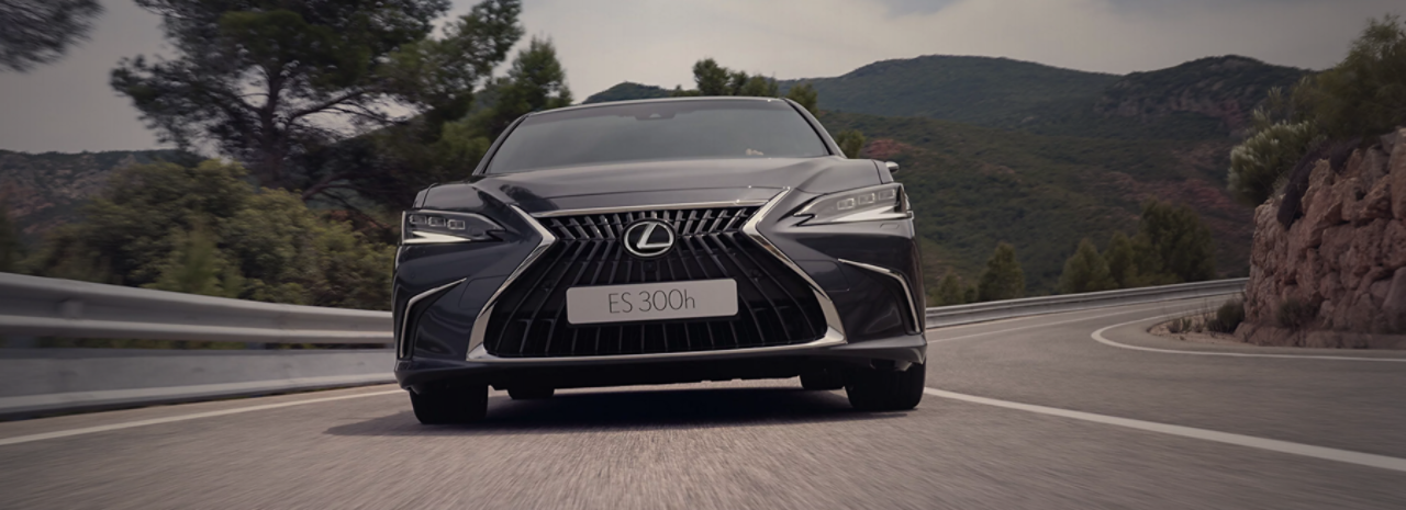 A Lexus ES driving down a country road showcasing its modern design and distinctive features.