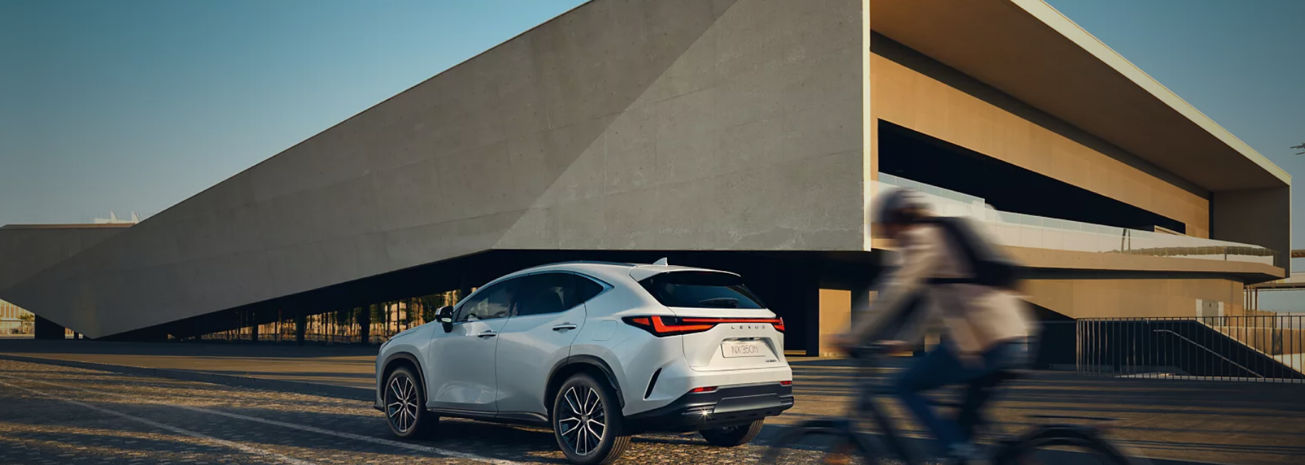 A white Lexus NX on a city street, showcasing its sleek design and urban appeal.