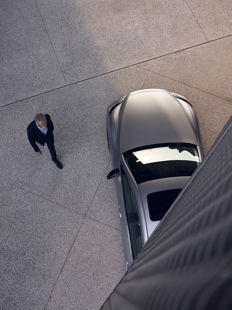 A business person in a suit walking past a Lexus.