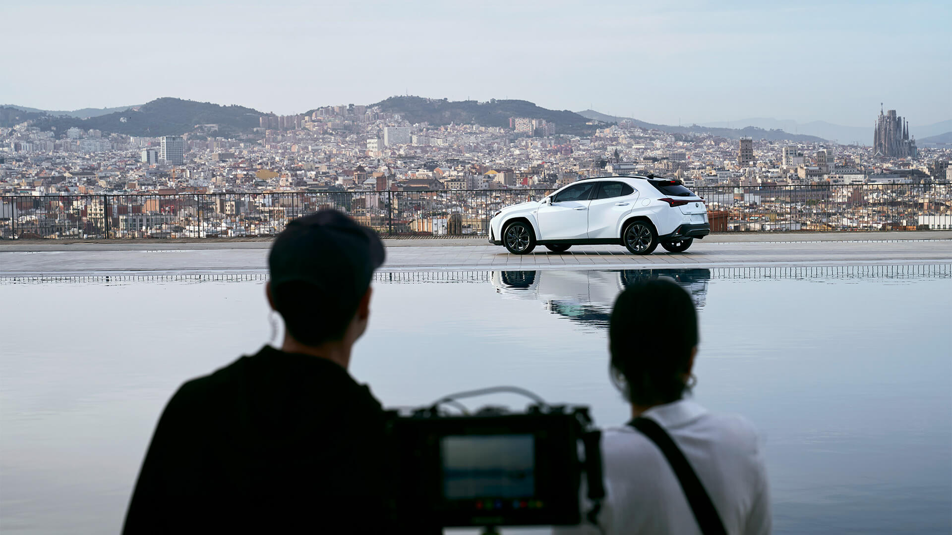 A man and woman in the forefront of a Lexus UX