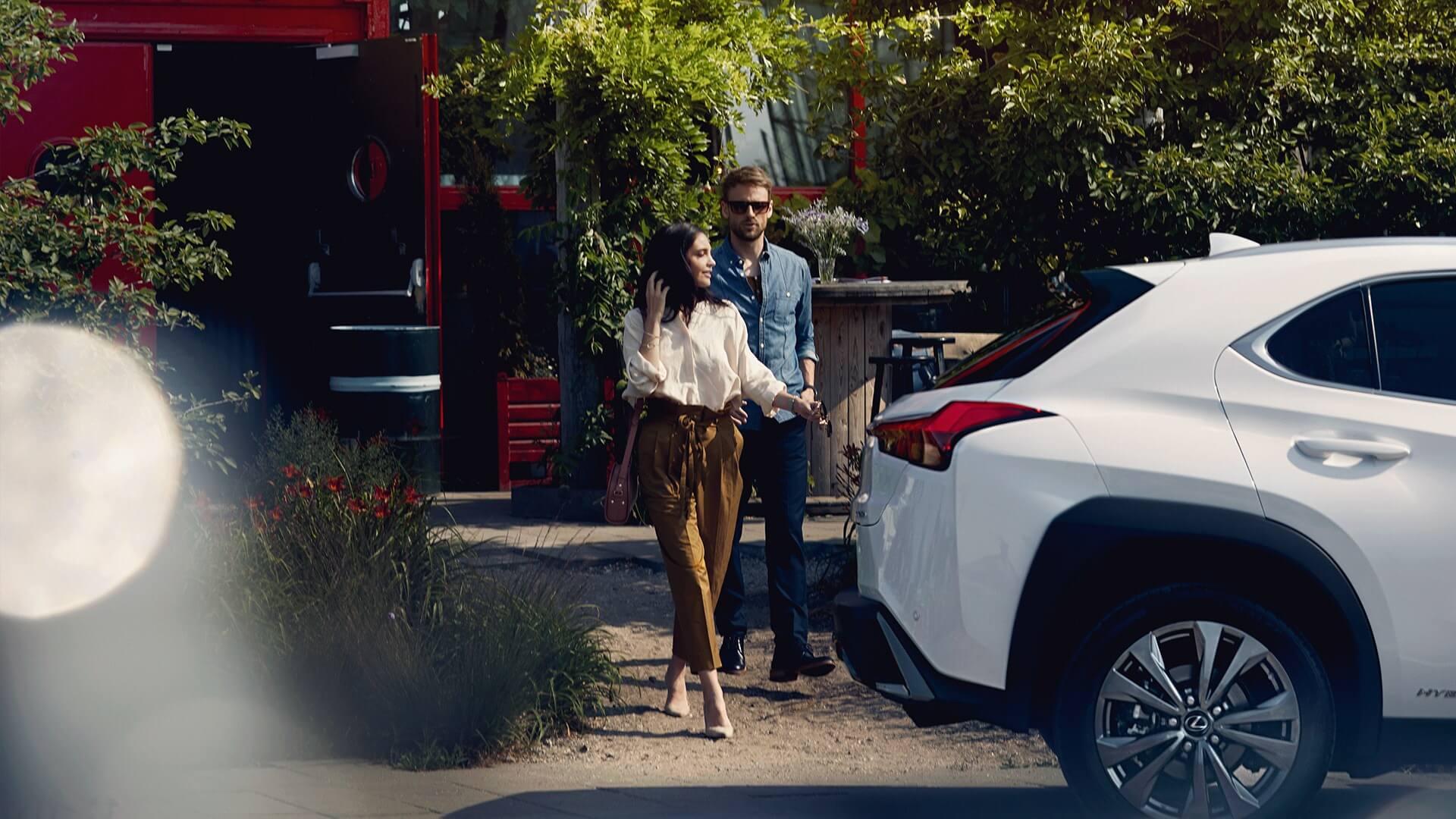 A man and woman standing by a Lexus